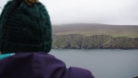 Woman-in-wooly-hat-looking-out-over-powerful-Scottish-Highlands-in-Shetland