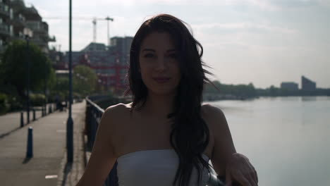 Beautiful-latina-woman-on-holiday-turning-and-smiling-at-the-camera-right-next-to-the-river-Thames-in-London