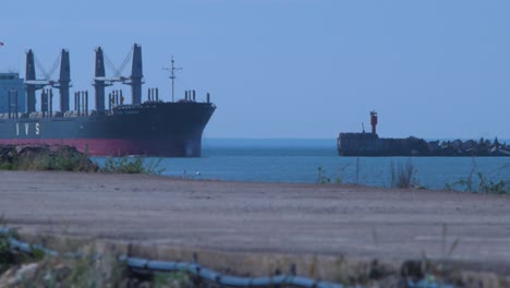 Forest---product-carrier-ship-arriving-at-Port-of-Liepaja-in-hot-summer-day,-distant-medium-shot-from-fort-pier