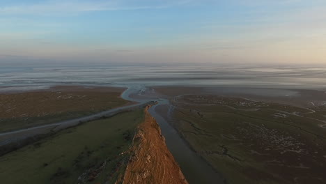Aerial-shot-of-British-coastline,-moving-forward-towards-the-sea,-shot-while-the-sun-was-setting