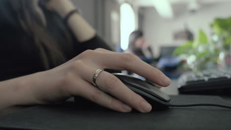 Low-contrast-footage-of-a-woman's-hand-as-clicking-and-scrolling-with-a-mouse-in-the-office