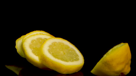 Geschnittene-Zitrone,-Die-In-Zeitlupe-Auf-Eine-Schwarz-Verspiegelte-Oberfläche-Fällt