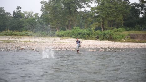 Alone-Indian-fisherman-catching-fishes-by-throwing-fishnet-in-river,-slow-motion