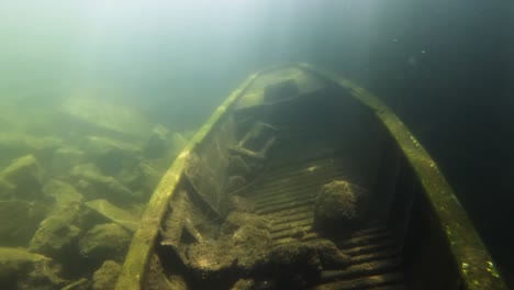 sunken-wreck-of-a-rowboat-on-the-bottom-of-a-flooded-freshwater-quarry-with-sunbeams-coming-from-top