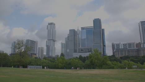 Pan-left-to-right-on-Austin,-Texas-skyline-with-people-running-and-walking-in-distance