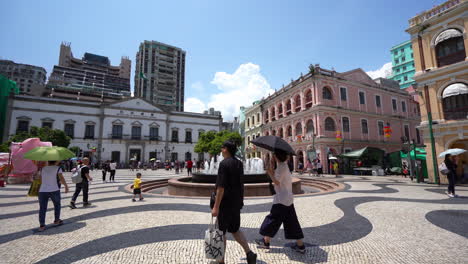 Tilt-shot-of-people-passing-the-fountain,-at-the-Senado-square,-in-Macao