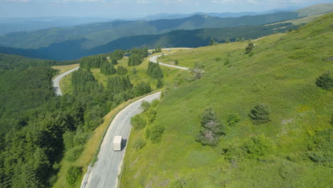 White-Truck-going-down-a-mountain-road-with-panoramic-view-of-hills