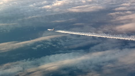 Incredible-view-from-the-cockpit-of-an-airplane-flying-high-above-the-clouds-leaving-a-long-white-condensation-vapour-air-trail-in-the-blue-sky