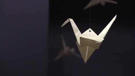 Origami-Kranich-Aus-Weißem-Papier,-Der-In-Einem-Dunklen-Raum-Hängt
