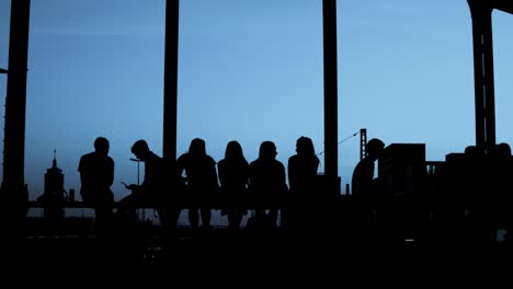 Silhouettes---Group-of-people-is-sitting-together-at-evening-light---camera-zoom-in---place-for-your-own-text---slow-motion