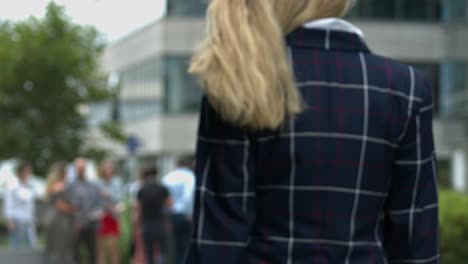 shallow-focus-close-up-of-young-business-woman-with-blonde-wavy-hair-walking-in-the-busy-city