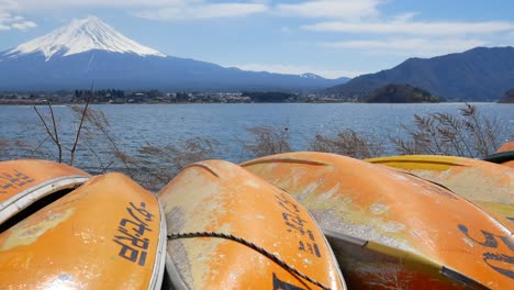 Blick-Auf-Den-Vulkanischen-Berg-Von-Fuji-Mit-Dem-Kawaguchi-see-Und-Einer-Orangefarbenen-Gruppe-Kleiner-Kanuboote-In-Der-Nähe-Des-Ufers-Im-Frühling-Bei-Klarem-Himmel