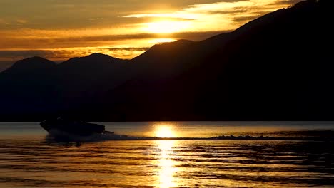 Orange-sunset-with-mountains-clouds-water-skier-in-background