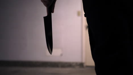 A-scary-slasher-killer-holding-a-kitchen-knife-in-silhouette-and-walking-towards-his-murder-victim-in-a-home-invasion-SLOW-MOTION