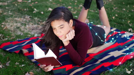 A-hispanic-woman-university-student-laying-outdoors-reading-and-studying-a-school-textbook-on-a-college-campus-SLOW-MOTION