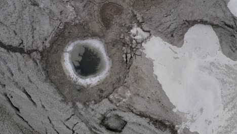 top-close-shot-of-flood-water-start-to-fill-sinkhole-with-muddy-water,-dead-sea-Israel,-aerial-view