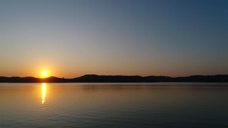 Entspannender-Sonnenuntergang-Im-Zeitraffer-über-Einem-Ruhigen-See-Mit-Bergen-Im-Hintergrund