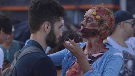 Close-up-of-a-make-up-artist-in-style-applying-prosthetics-before-Halloween-walk-of-zombies-on-the-Day-of-the-Dead-in-Copacabana