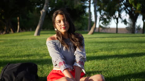 Beautiful-young-hispanic-college-student-resting-on-a-grassy-park-field-on-a-calming-sunny-day