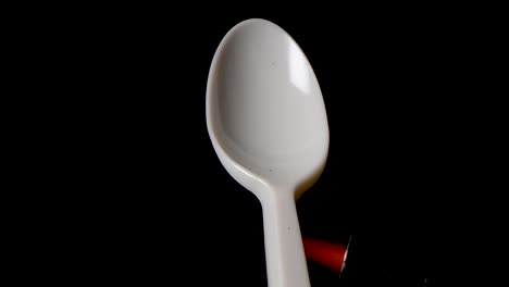 Flame-melts-handle-of-a-plastic-spoon-in-front-of-black-background