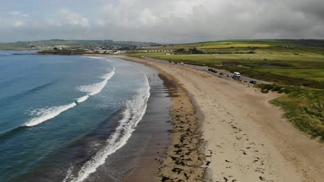 Aerial-footage-over-sandy-beach-with-waves-and-grassy-dunes
