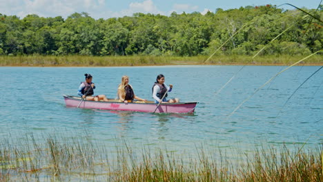 Slow-motion-of-three-girls-canoeing-on-the-lake-in-Chunyaxche,-Quintana-Roo,-Mexico