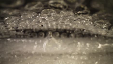 pulling-out-of-a-bubble-wrap-bag,-top-of-the-bag-moves-slightly,-focused-on-the-top-third-of-the-bag