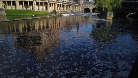 Empire-Hotel,-Pulteney-Weir---Pulteney-Bridge-in-Bath,-Somerset-on-a-Beautiful-Summer’s-Morning-fading-in-from-the-River-Avon