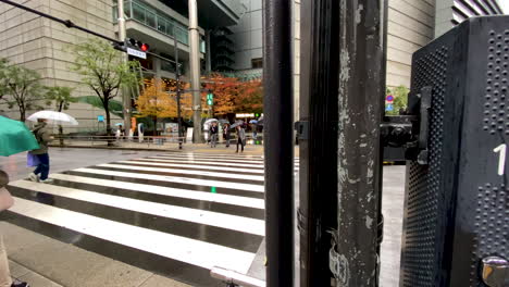 Slow-motion-shot-of-Japanese-people-crossing-road-using-zebra-crossing-in-Tokyo,-Japan-during-rainy-day,-trucking-movement