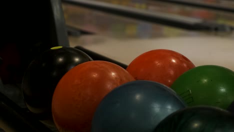 Closeup-of-hand-picking-up-bowling-ball-and-putting-it-back-at-indoors-bowling-alley