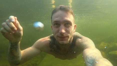 A-young-man-films-himself-with-an-action-camera-as-he-takes-a-deep-breath-and-dives-into-the-cold-Norwegian-water-during-a-hot-summer-day