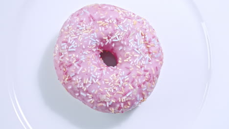 Weitwinkelaufnahme-Eines-Rosafarbenen-Donuts,-Der-Sich-Auf-Einem-Weißen-Teller-Dreht