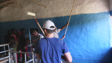 Group-of-local-volunteers-and-charity-event-members-painting-inside-school's-classroom-wall-in-Ziway,-Ethiopia
