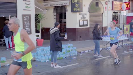 Volunteers-handing-out-water-and-cheering-up-the-marathon-runners-in-city-center-of-Malaga,-Spain