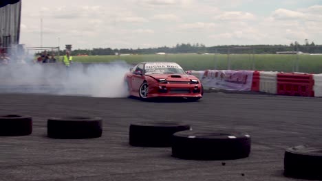 Red-Nissan-240SX-drifting-on-a-drift-track-in-super-slow-motion-with-lots-of-smoke-from-the-tyres-in-a-close-up-shot