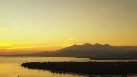 Gelber-Sonnenuntergang-Einer-Kleinen-Insel,-Eines-Großen-Gewässers-Und-Der-Berge-Im-Beliebten-Urlaubsort-Lombok,-Indonesien