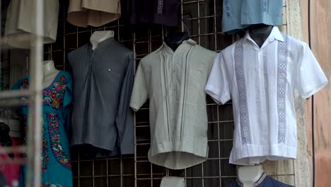 Camera-pans-up-showing-assortment-of-street-vendor’s-display-of-guayabera-men’s-shirts-in-Merida-Mexico