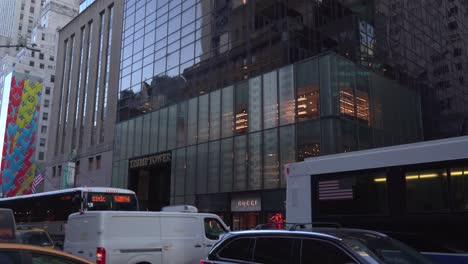 Trump-Tower-in-Manhattan-With-Traffic-and-People-Passing-by,-Wide-View-Pan-Up-Toward-Sky