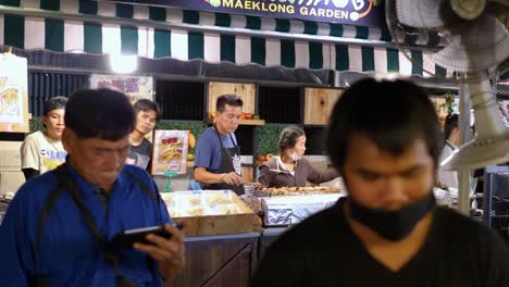 Group-of-people-working-on-street-food-stall,-night-market-Bangkok