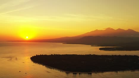 Sun-going-down-over-a-large-body-of-water,-creating-golden-light-in-mountain-of-Indonesia