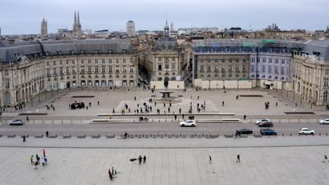 Place-de-la-Bourse-in-Bordeaux-France-with-people-on-its-square-walking,-Aerial-lift-pedestal-shot