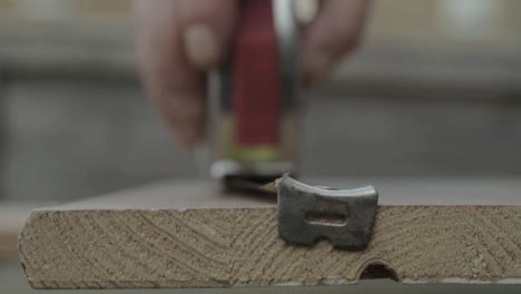 Workman-hand-using-metal-tape-measure-to-measure-piece-of-wood