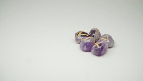 Five-Purple-Birthstones-With-Engraved-Symbols-And-Letters-On-Top---Close-Up-Shot