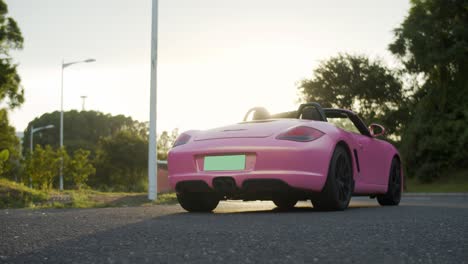 Porsche-Boxster-De-Color-Rosa-Estacionado-En-La-Carretera-Al-Atardecer