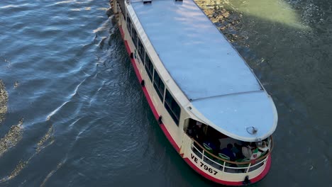 Boat-With-Passengers-Cruising-At-The-Grand-Canal-In-Venice,-Italy---high-angle-slowmo-shot