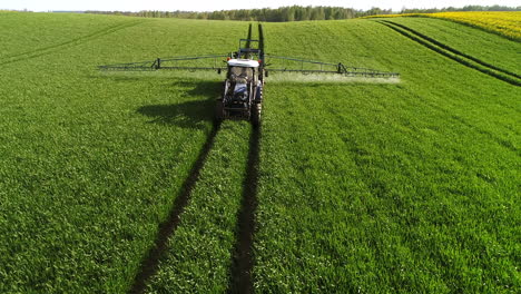 Close-drone-shot-of-farming-tractor-plowing-and-spraying-on-field