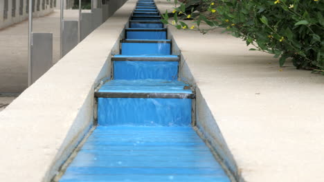 Wasser,-Das-Ein-Künstliches-Wasserspiel-Mit-Blauen-Stufen-Hinabstürzt,-Nach-Oben-Kippen