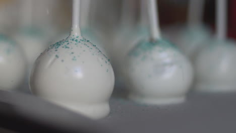 Close-up-of-white-cake-pops,-edible-pastry-glitter-falling-on-them,-slow-motion-120fps