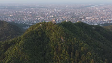 Gifu-castle-on-Mt-Kinka,-Slow-Aerial-reveal-ancient-building-and-Japanese-city