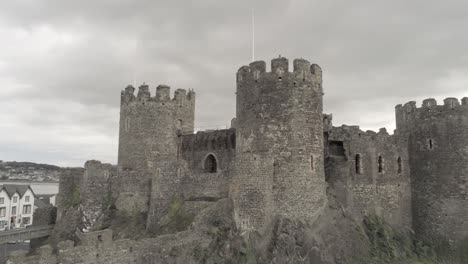 Medieval-landmark-historic-Conwy-castle-aerial-view-above-Welsh-seaside-landscape-pan-right-tilt-up